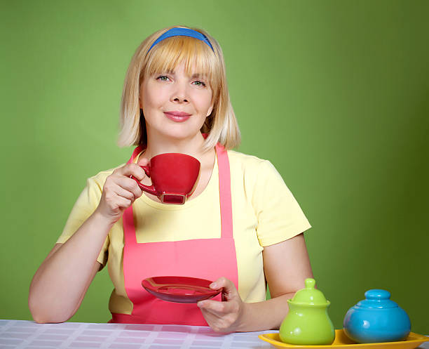 housewive  at home sipping tea from a  red cup stock photo