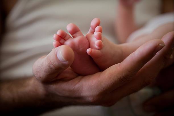 istock Baby feet in fathers hands 153724333