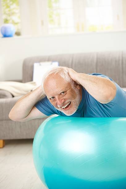 Happy active senior exercises on fit ball