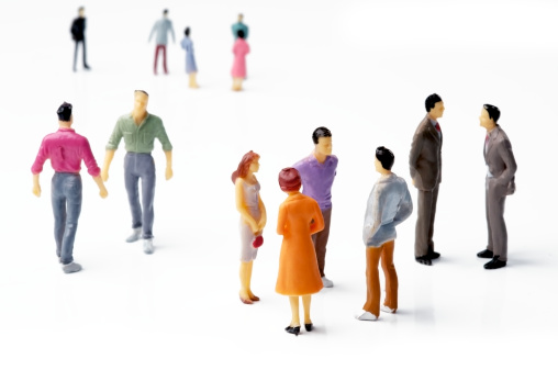 A group of model people dressed brightly, chatting amongst themselves on a white backdrop