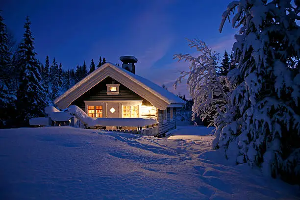 Cottage covered with snow and illuminated in the polar night.