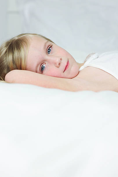 Little girl laying on a bed stock photo