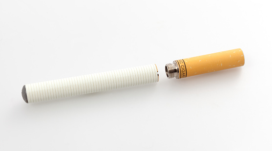 Electronic Cigarette on White Background showing electronic filter. The sigarette is white and the electronic filter is orange. This looks like a real cigarette except for the charge part. The picture was taken in a light table on a white background.
