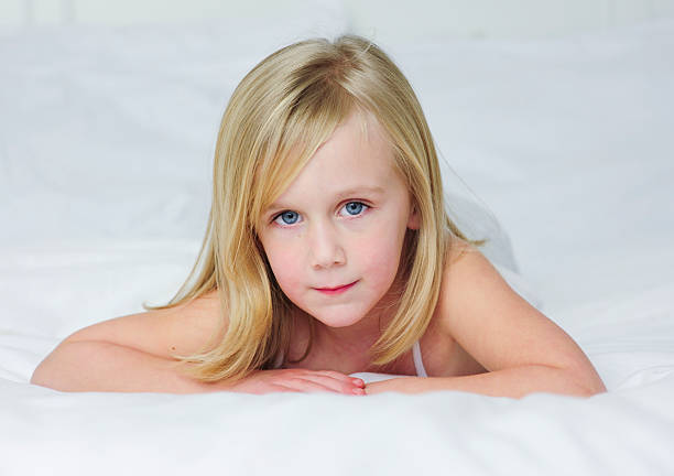 Little girl laying on a bed stock photo