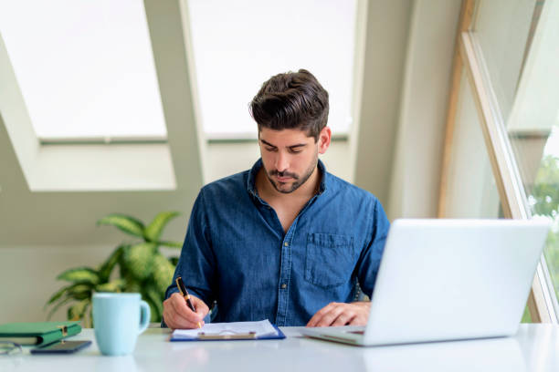 istock A stubbled faced man sitting at the table and looking thoughtful while working on laptop 1537299201