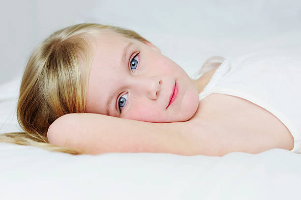 Little girl laying on a bed stock photo