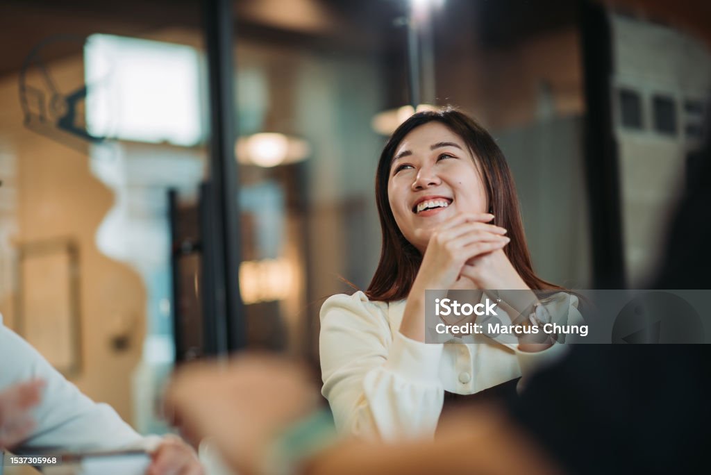 Asian chinese beautiful young woman toothy smile during discussion with team at meeting room close up of young female adult looking away with smiling face Asia Stock Photo