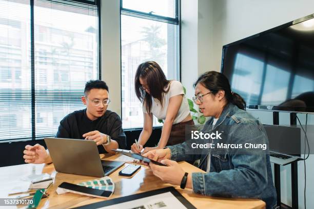 Small Group Of Asian Chinese Graphic Designer Working Together In Their Design Studion Stock Photo - Download Image Now