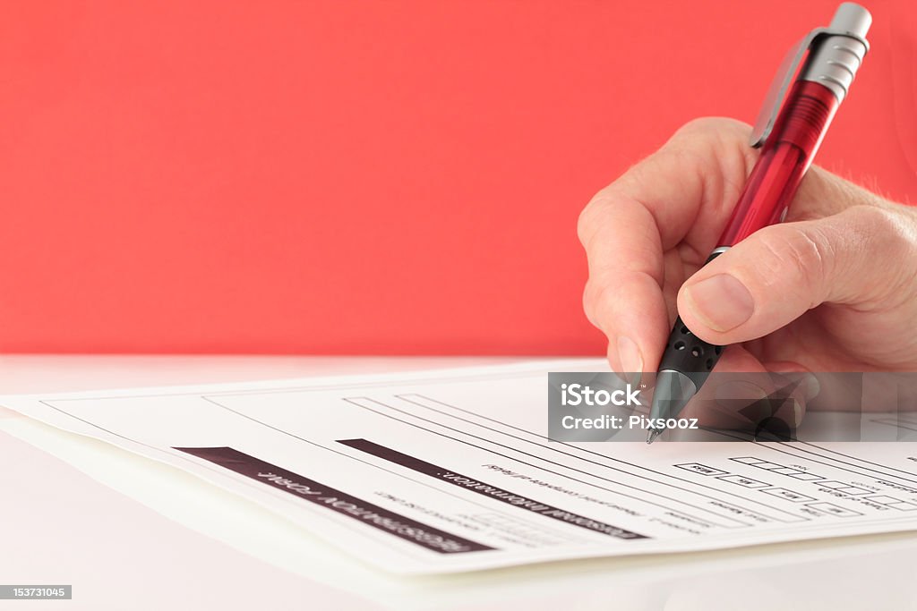 Red Themed Pen in Hand Completing Form Hand with red pen completing form on red background Application Form Stock Photo
