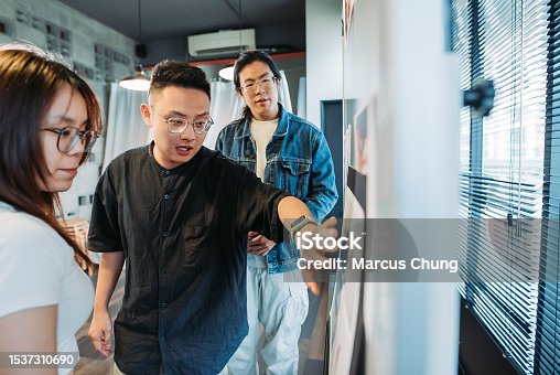 istock Small group of asian chinese designer working together in front of whiteboard in their design studio 1537310690
