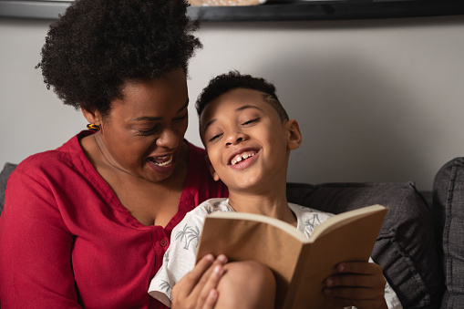 Mother and young boy have fun reading book in home room
