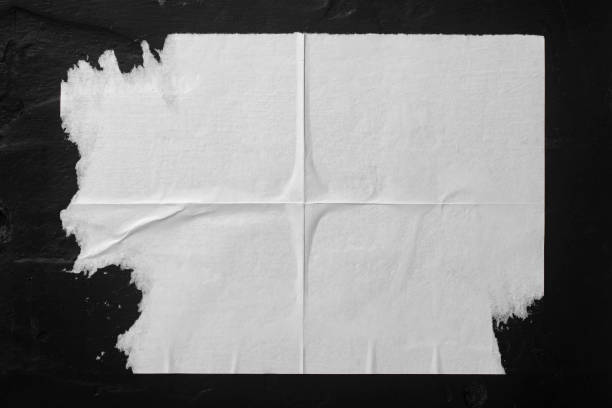 istock White paper with folds on a black wall. 1537315795