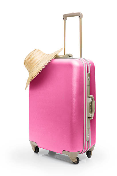 Summer time travel with pink suitcase and straw hat 