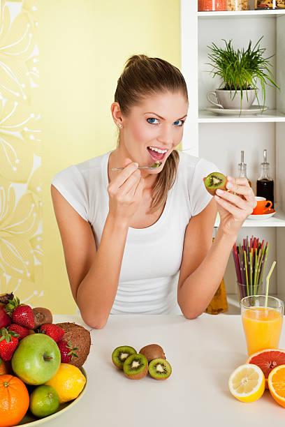 Young beauty woman eating kiwi stock photo