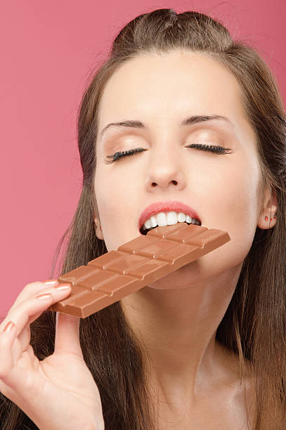 istock Young woman bites chocolate 153732332
