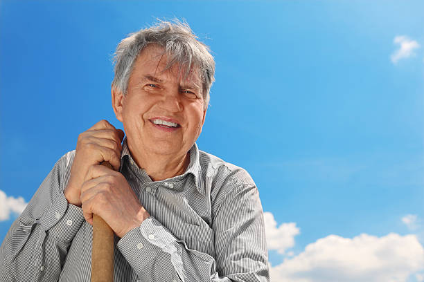 istock Senior in striped shirt with shovel smiling 153732403
