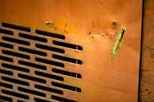 Authentic old style industrial background. Close-up of a dirty part of an old road roller. Orange colored metal.