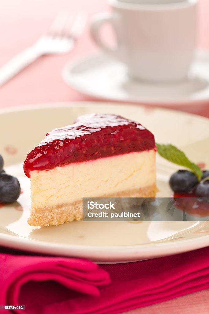 Rasberry cheese cake Piece of rasberry cheese cake in a plate with  fork and coffee cup in the background. Extremely shallow depth of field. Baked Pastry Item Stock Photo