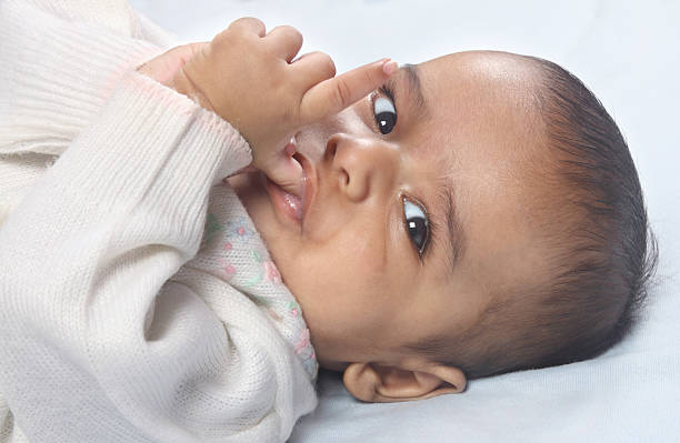 インドの 4 ヶ月の赤ちゃん - finger in mouth 写真 ストックフォトと画像