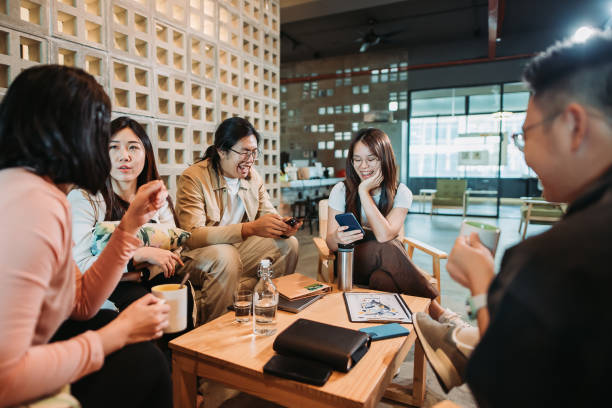 istock Asian chinese group of creative team chilling on office sofa area using phone 1537341924