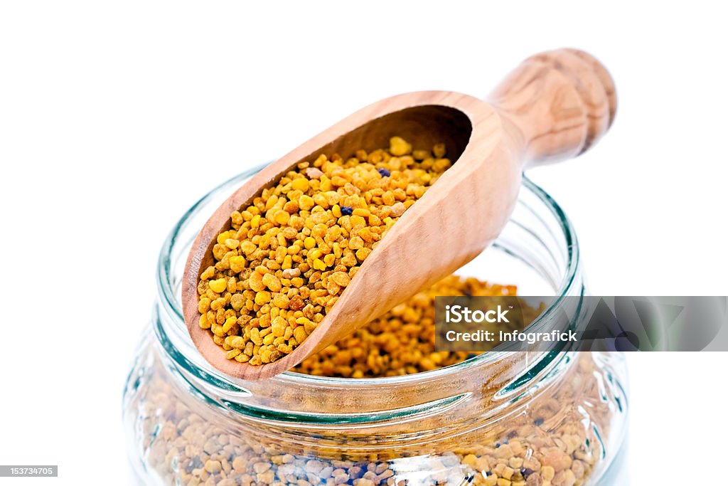 Wooden scoop and bee pollen Closeup of a wooden scoop and a glass jar of bee pollen, on white background Bee Stock Photo