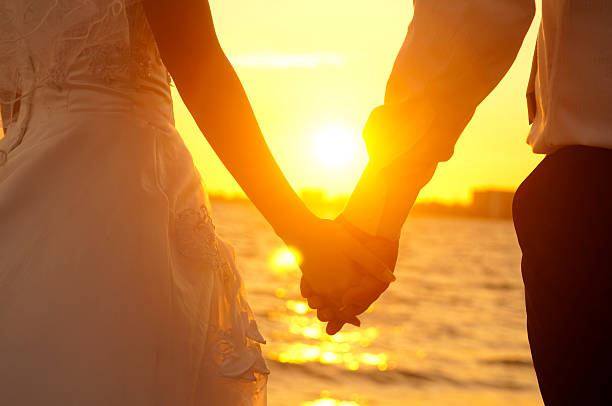 istock Bride and groom holding hands in front of a sunset 153735037