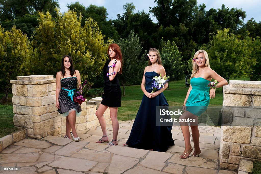 4 Young Woman in Evening Wear Four young women in evening wear are ready and happy for the prom or a night on the town. All are wearing or holding floral arrangements Fashion Stock Photo