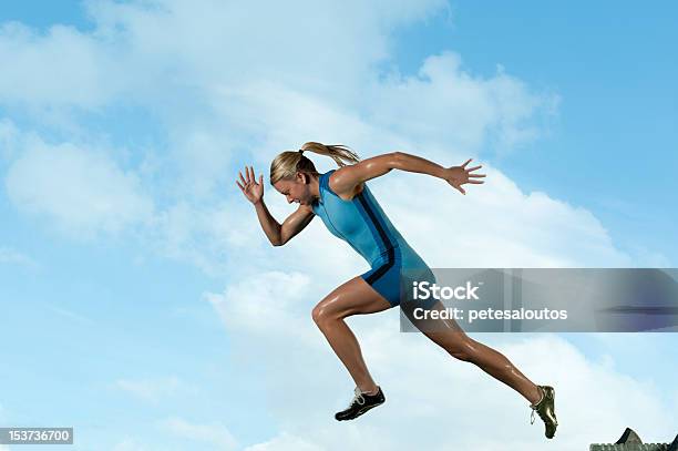 Female Sprinter Running In Front Of A Blue Sky Stock Photo - Download Image Now - Blue, Running, Sports Track