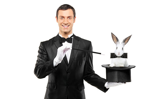 Magician holding a top hat with rabbit in it A magician in a black suit holding a top hat with a rabbit in it isolated on white background formal glove stock pictures, royalty-free photos & images