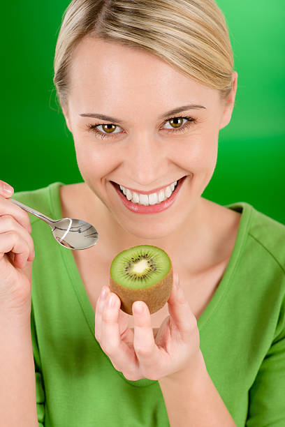 Healthy lifestyle - happy woman holding kiwi on green stock photo