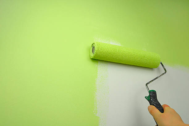 istock Hand painting a wall in green paint using a roller 153739945