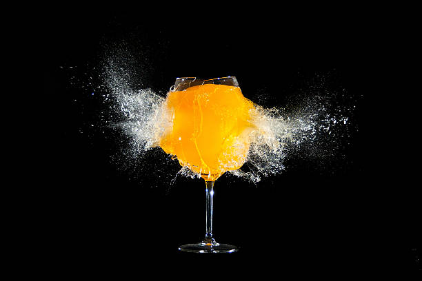 Glass with orange juice explosions at the black background