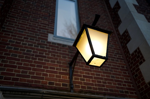 Princeton, NJ, USA-Yellow street light on the brick wall at dusk