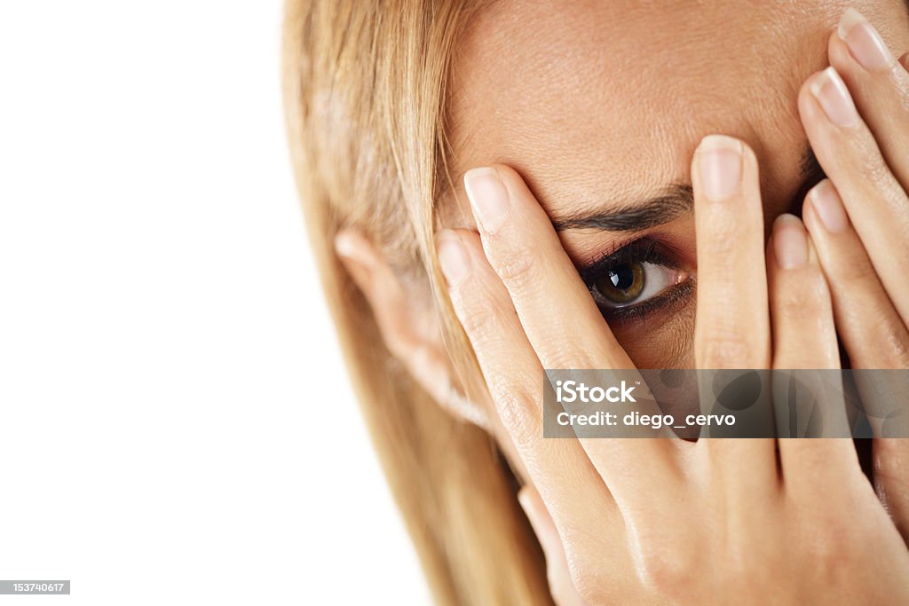 shy woman looking through fingers closeup of worried caucasian woman on white background. Horizontal shape, headshot 30-34 Years Stock Photo