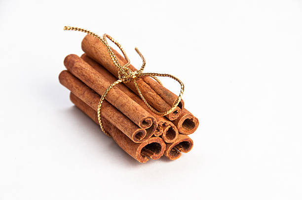 Cinnamon sticks with gold ribbon on white background stock photo