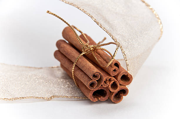 Stack of cinnamon sticks decorated with gold ribbons stock photo