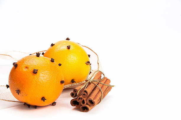Two cloves-decorated oranges and cinnamon sticks stock photo