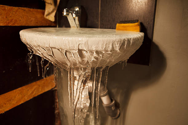 Frozen water spilling out of restroom sink stock photo