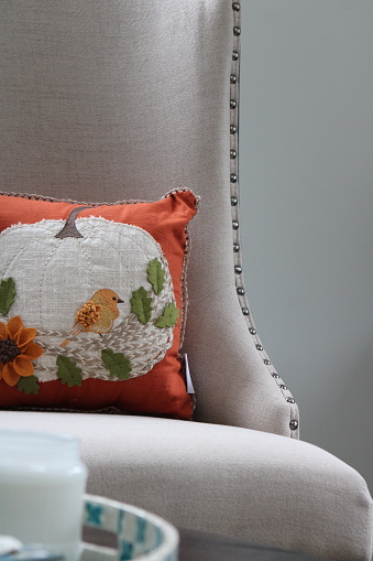 An autumn themed pillow with a bird embroidered onto it.