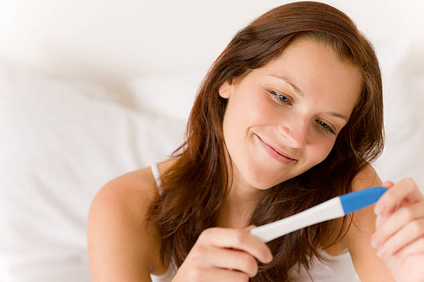 istock Smiling woman holding a pregnancy test 153744250