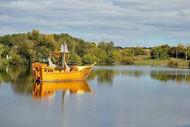 age-old wooden sailing-vessel on a lake, autumn