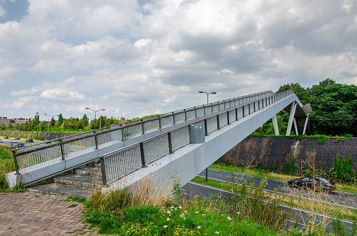 Vught, The Netherlands, July 10, 2023: steel pedestrian bridge, crossing both a busy road and a railway track