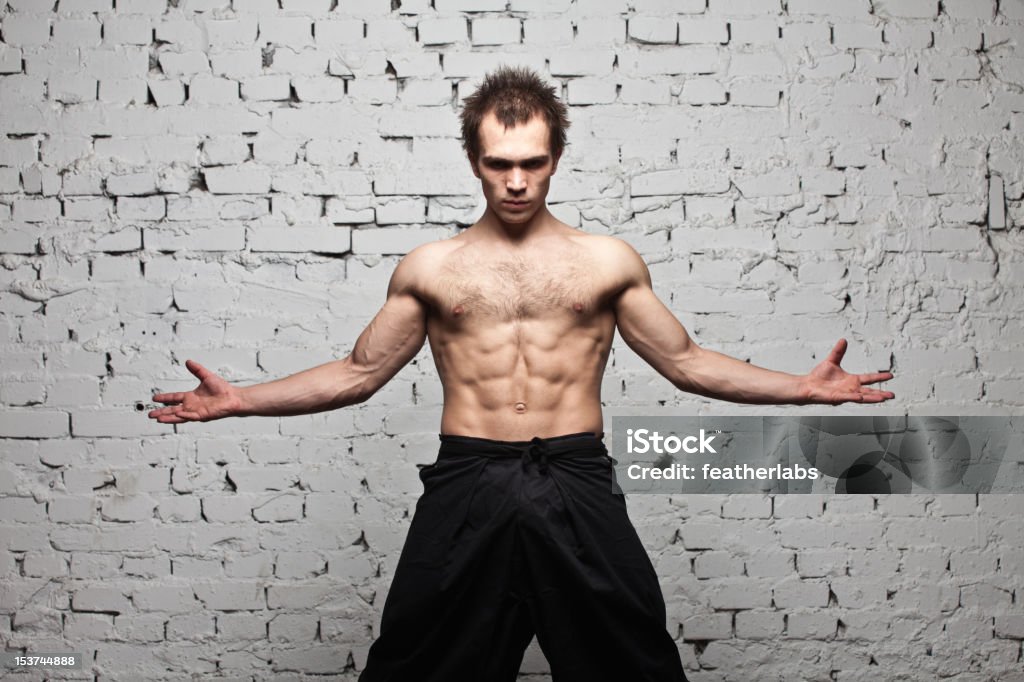 Forza muscolare uomo soggiorno in bianco muro di mattoni - Foto stock royalty-free di A petto nudo