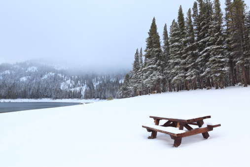 Winter view of a lakeside picnic table at Mammoth Lakes in Sierra Nevada mountains of California