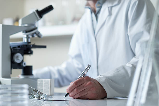 scientist conducting research with microscope stock photo