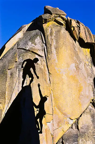 Team of climbers reaching the summit of a rock pinnacle.