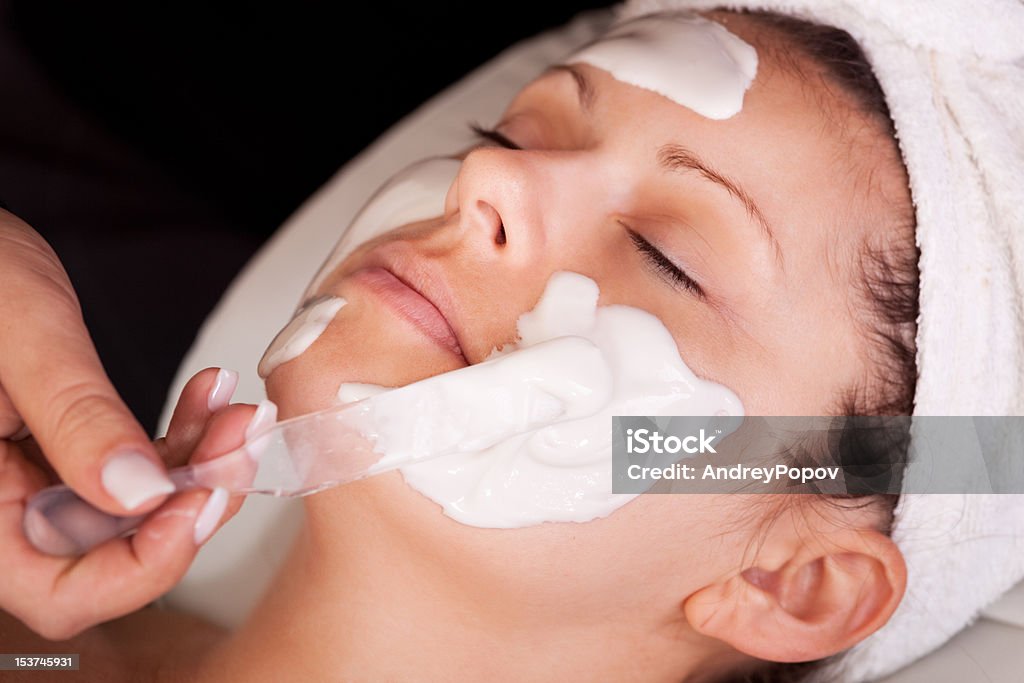 Giovane donna ottenere trattamento viso Maschera - Foto stock royalty-free di Adulto