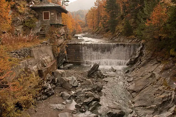 Autumn at a small cottage and man-made waterfall on the torrente urtier near Lillaz in the Cogne Valley of the Parc Nationale Gran Paradisio in the Valle D'Aosta region of northern Italy.