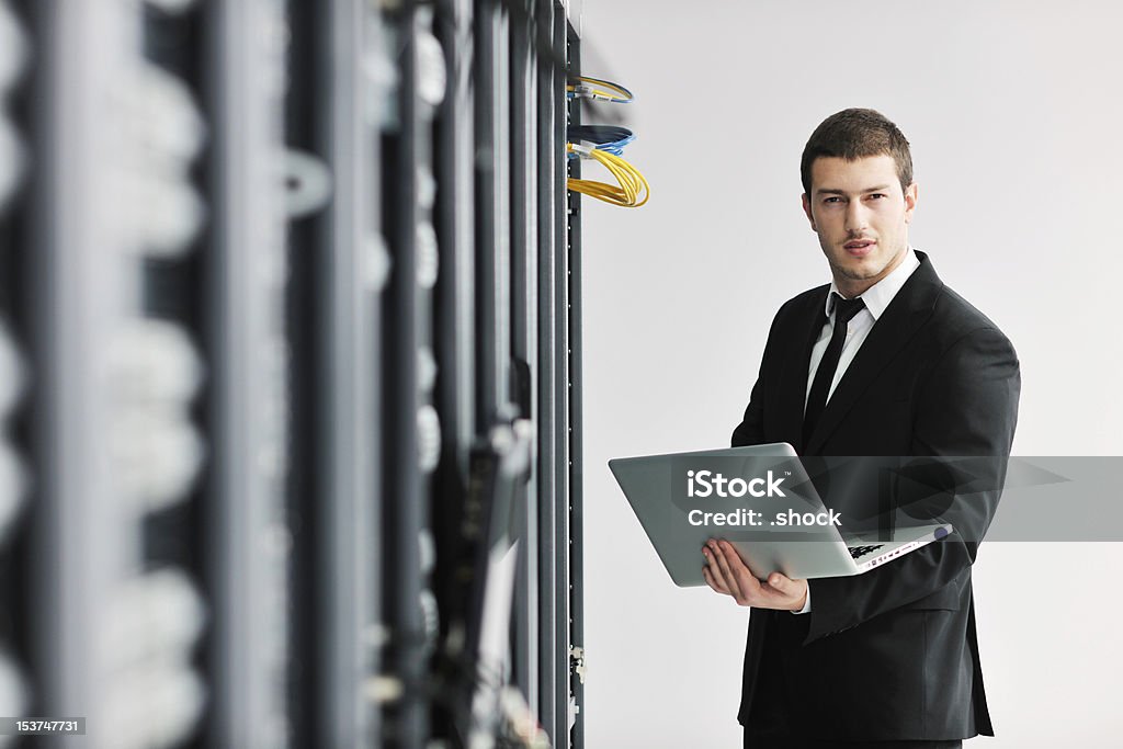 Hombre de negocios con ordenador portátil en la sala de servidores de red - Foto de stock de Adulto libre de derechos