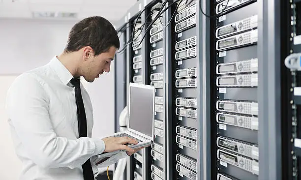 Photo of Young businessman with laptop in server room